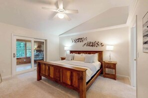A bedroom with a wooden bed, a ceiling fan, a nightstand, and a wall-mounted lamp. - New listing - lakefront home with views, dock, fireplace, foosball, deck, & W/D (Eagle River)