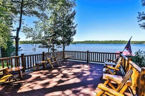 Eine Holzterrasse mit Stühlen und Tischen mit Blick auf einen See.