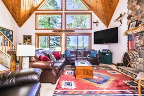 Ein gemütliches Wohnzimmer mit großem Fenster, Kamin und Fernseher.