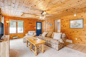 A wooden cabin interior with a sofa, coffee table, and a ceiling fan. - Lakefront, dog-friendly home with dock, kayaks, deck, & washer/dryer (Eagle River)