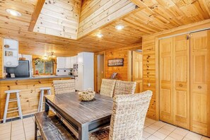 A wooden interior with a dining area, kitchen, and a large wooden door. - Lakefront, dog-friendly home with dock, kayaks, deck, & washer/dryer (Eagle River)