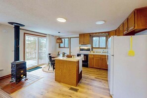 A kitchen with wooden cabinets, a central island, a stove, and a refrigerator. - Two Pickerel Lake cabins w/ kayaks, dock, patio, grill & direct access to trails (Eagle River)