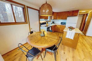 A kitchen with wooden cabinets, a round dining table, and a hanging light fixture. - Two Pickerel Lake cabins w/ kayaks, dock, patio, grill & direct access to trails (Eagle River)