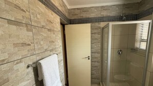 Une salle de bain avec une douche, des toilettes et une serviette accrochée au mur.