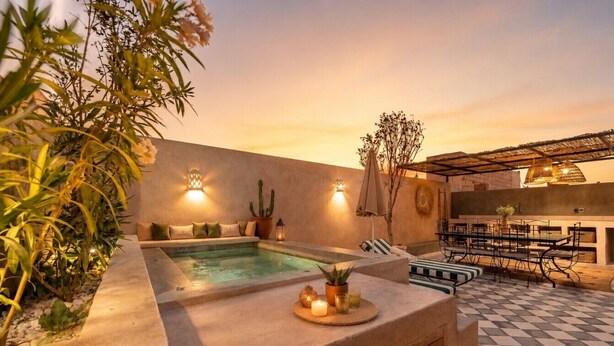 A pool area with a checkered floor, a lounge with a table and chairs, and a wall-mounted light fixture. - Dar Shihab exclusive - breakfast included - swimming pool (Marrakech)