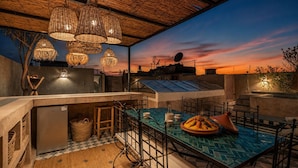 An outdoor dining area with a checkered floor, a table with a woven basket, and hanging wicker lamps. - Dar Shihab exclusive - breakfast included - swimming pool (Marrakech)
