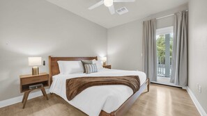 Ein Schlafzimmer mit Bett, Nachttischlampen, einem Nachttisch, einem Deckenventilator und einem Fenster mit Vorhängen.