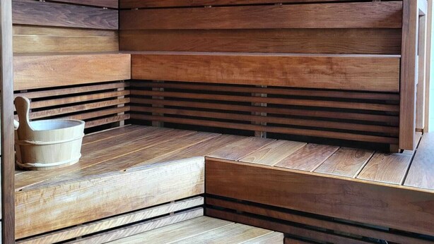 A sauna with wooden benches and a small wooden bucket. - EnjoyNature Resort (Hollola)