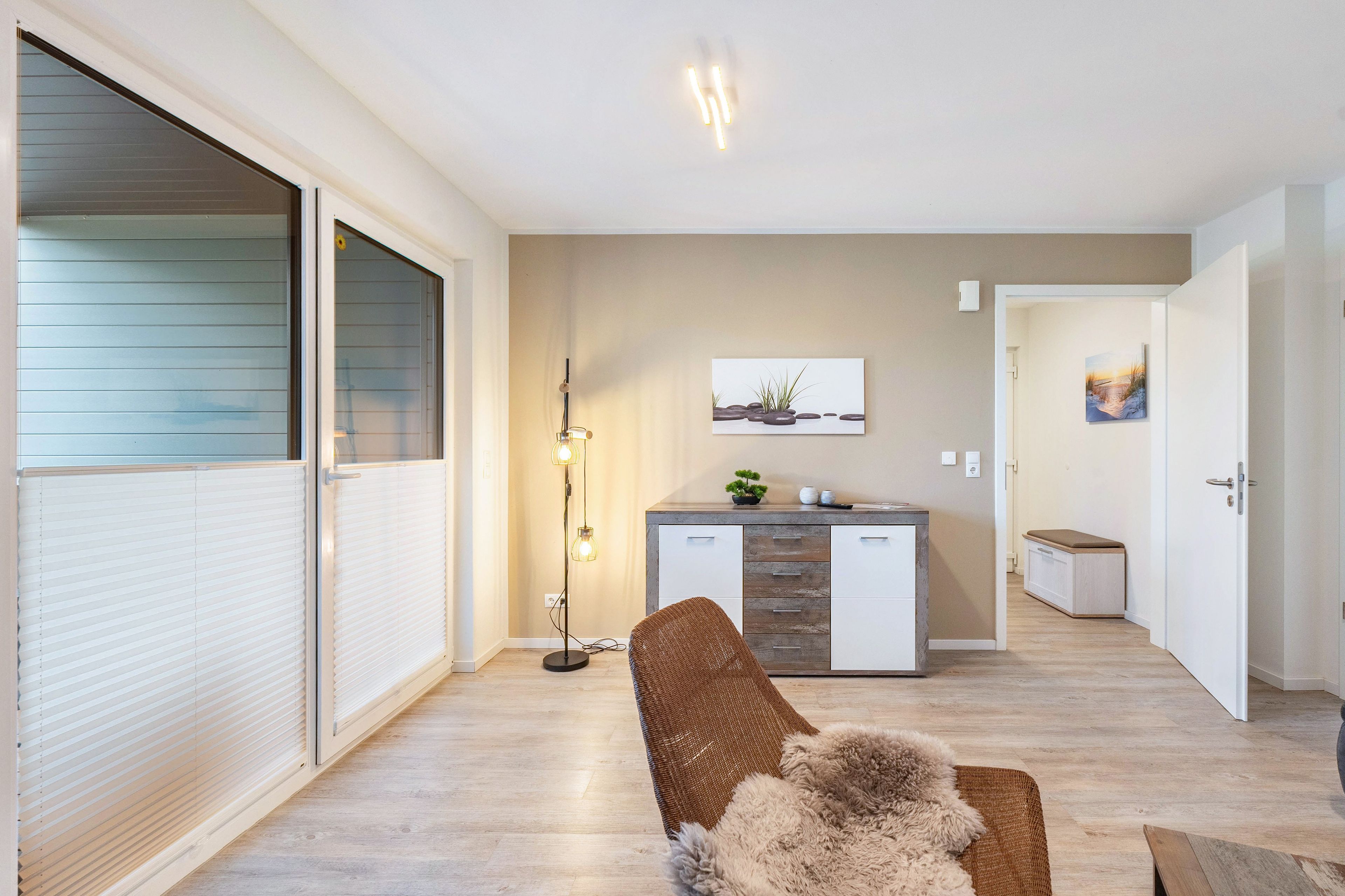 A modern living room with a sofa, a floor lamp, and a painting on the wall.