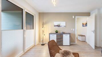 A modern living room with a sofa, a floor lamp, and a painting on the wall.