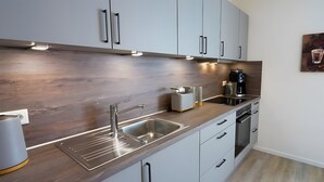 Una cocina moderna con electrodomésticos de acero inoxidable, horno empotrado y cafetera.