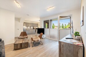Una sala de estar moderna con un televisor grande, dos sillones y una mesa de centro de madera.