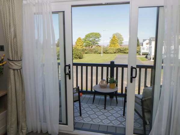 A balcony with a patterned floor, a small table with a potted plant, and a chair. - Santa Maria (Llandysul)