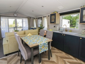 A compact living space with a sofa, dining table, and kitchenette. - Santa Maria (Llandysul)