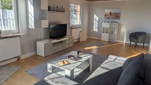 Ein modernes Wohnzimmer mit Flachbildfernseher, Einbauschränken, einem grauen Sofa und einem Couchtisch.