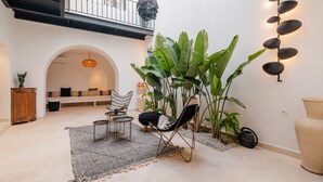Ein großzügiger Wohnbereich mit hohen Decken, einem Balkon und einer Sitzecke mit Sofa und Sesseln.