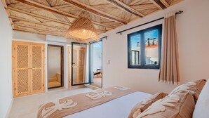 Ein Schlafzimmer mit einem großen Bett, Holzboden, einem Fenster mit Aussicht und einer Schiebetür zu einem Außenbereich.