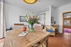 Ein Essbereich mit einem Holztisch, einer Blumenvase und einem Korbstuhl.