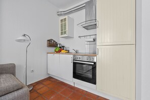 Una cocina funcional con estufa, horno y una pequeña encimera con utensilios de cocina.