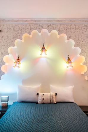 A bed with a patterned bedspread, two pillows, and two wall-mounted lanterns. - Riad iksandar prestige, Medina, heated pool (Marrakech)