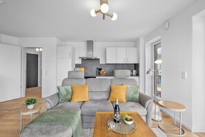A modern living room with a grey sofa, a wooden coffee table, and a small side table with a plant. - The View A08 Belvedere Nordsee - Balcony,sea view,garden furniture,shared. Sauna (Dagebüll)