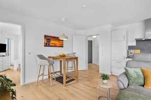 A modern living room with a dining area, a kitchen, and a hallway. - The View A08 Belvedere Nordsee - Balcony,sea view,garden furniture,shared. Sauna (Dagebüll)