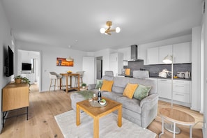 A modern living room with a grey sofa, wooden coffee table, and a TV on the left. - The View A08 Belvedere Nordsee - Balcony,sea view,garden furniture,shared. Sauna (Dagebüll)