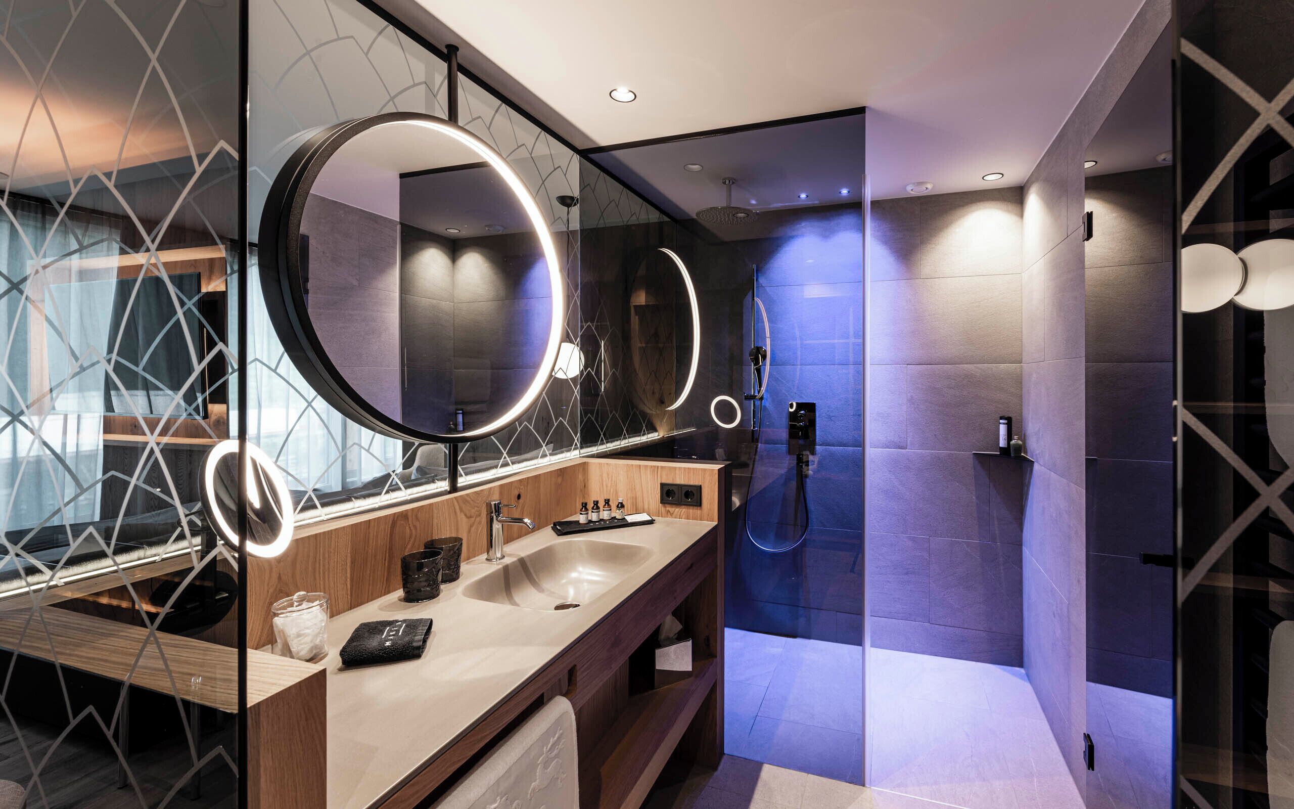 Une salle de bain moderne avec un meuble-lavabo, deux vasques, un grand miroir et un espace douche.