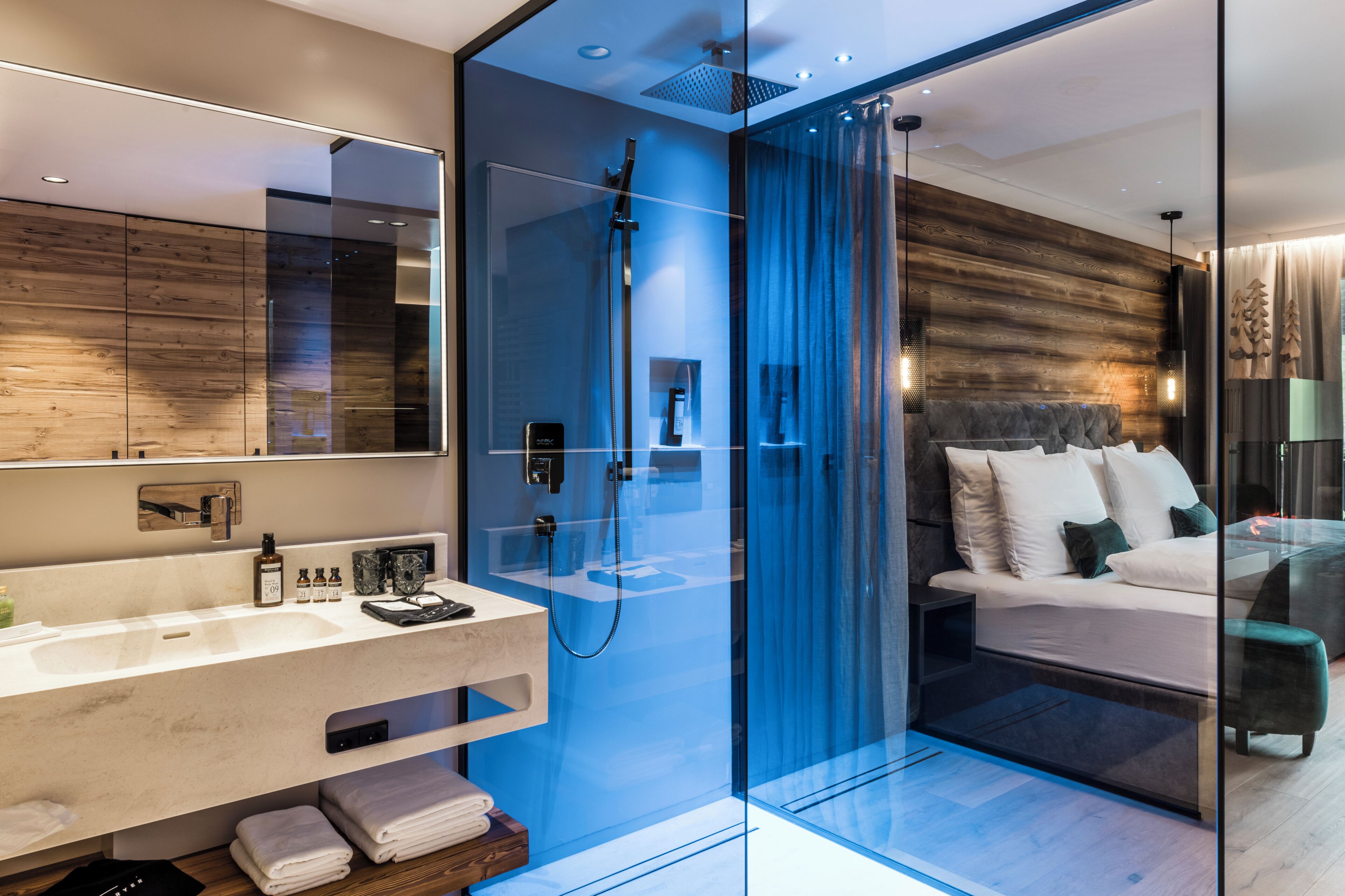Un bagno moderno con cabina doccia in vetro, un mobile lavabo con specchio e un letto con testiera.