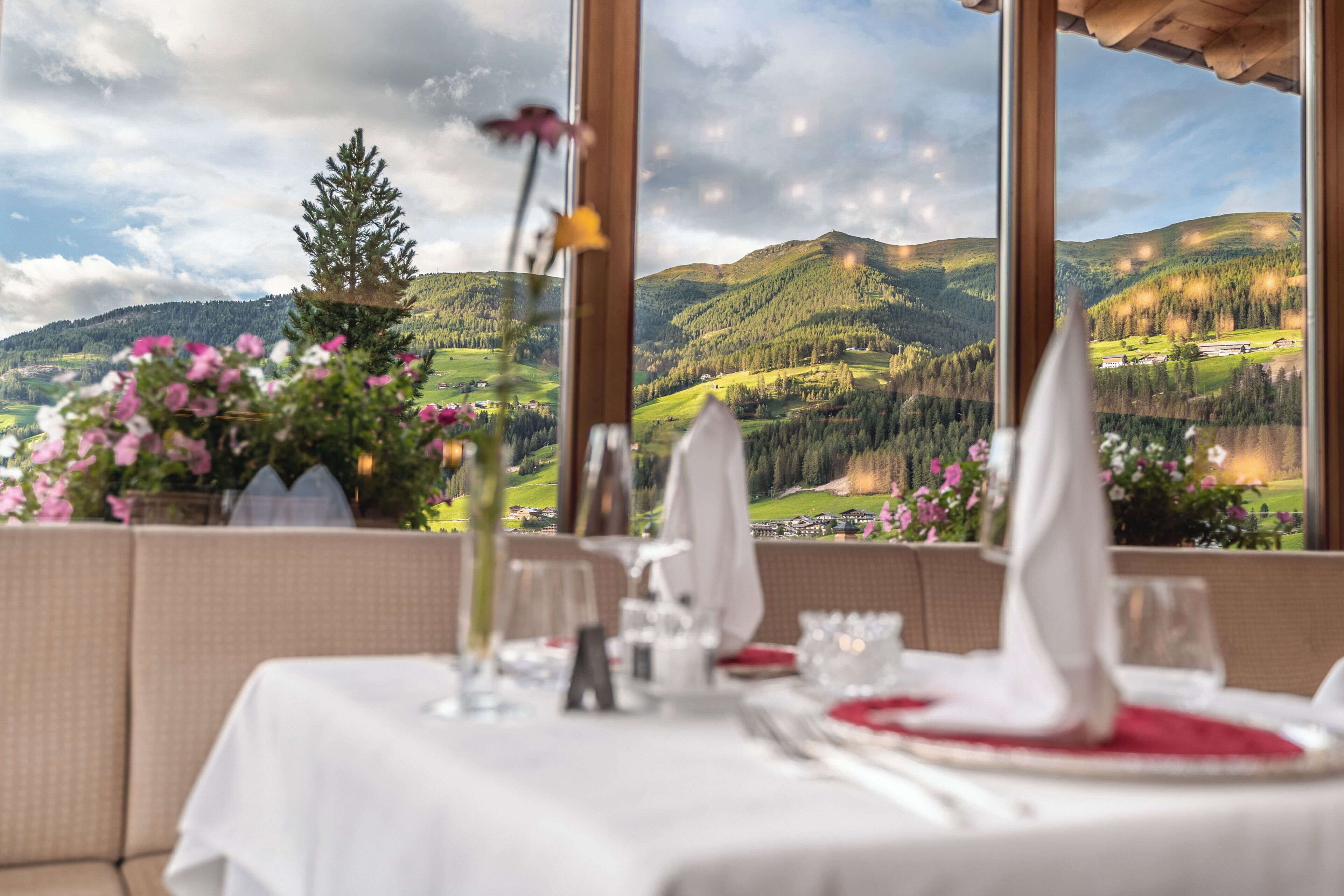A dining table set for two with a scenic mountain view through large windows.