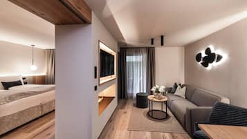 A modern hotel room with a bed, sofa, and a small table with a vase of flowers.