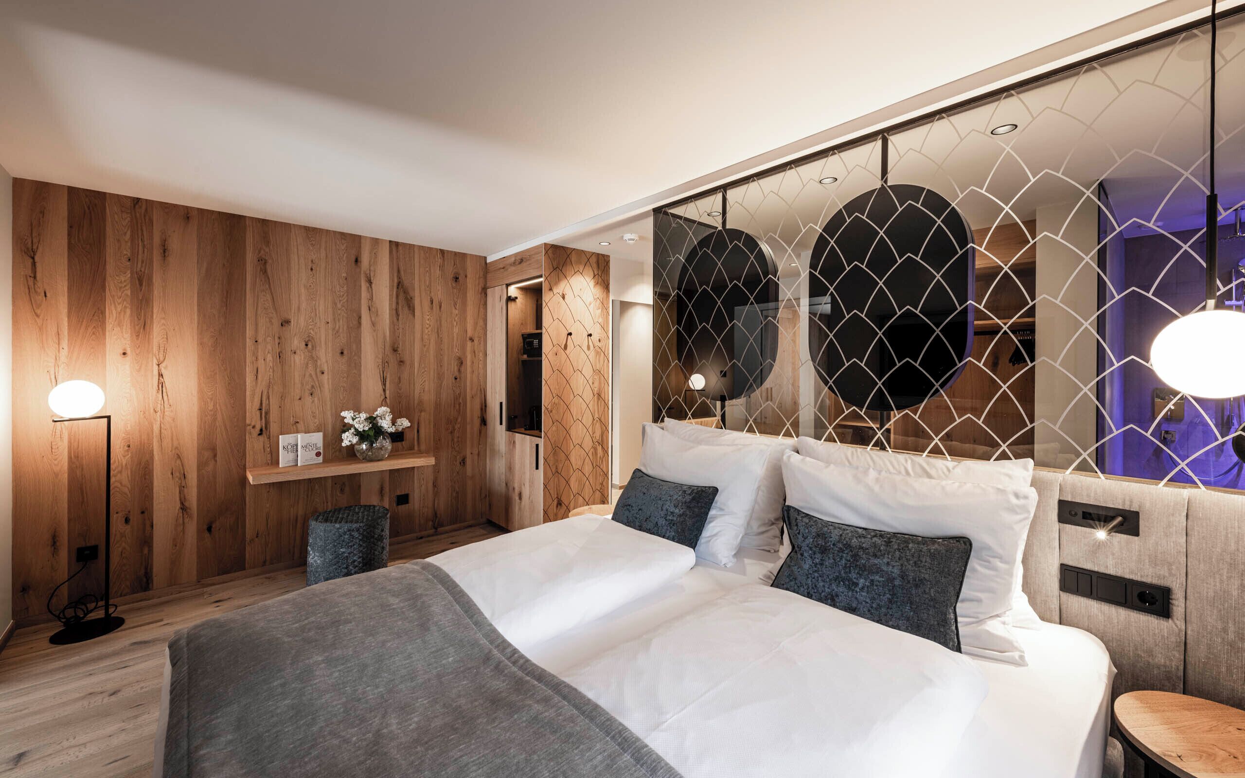 A modern bedroom with a wooden wall, a bed with white bedding, and a nightstand.