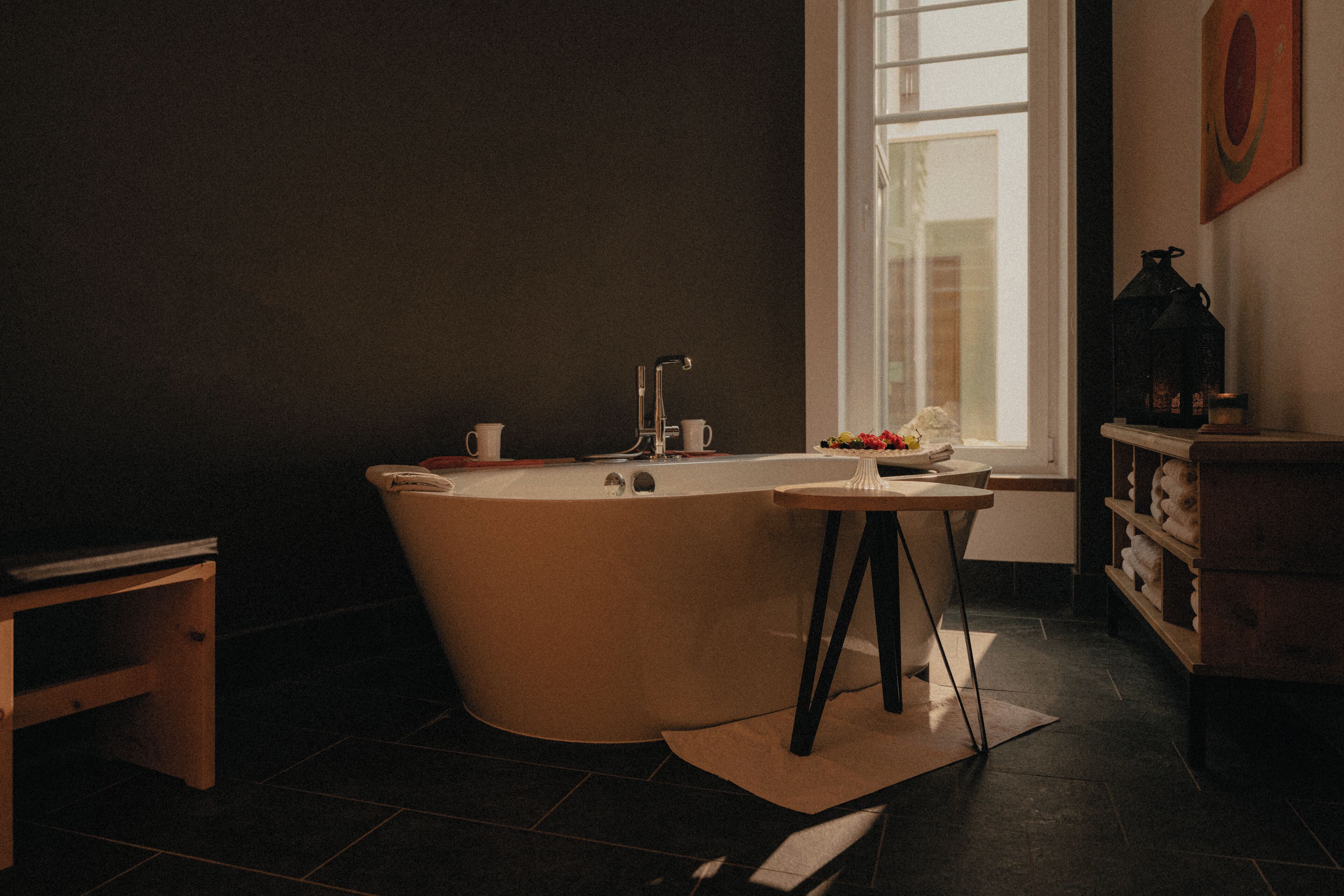 Une salle de bain moderne avec une baignoire sur pieds, un lavabo et une fenêtre laissant entrer la lumière naturelle.