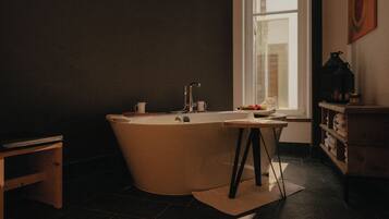 Une salle de bain moderne avec une baignoire sur pieds, un lavabo et une fenêtre laissant entrer la lumière naturelle.