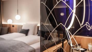 Una habitación de hotel moderna con cama, mesita de noche y espejo de diseños geométricos.