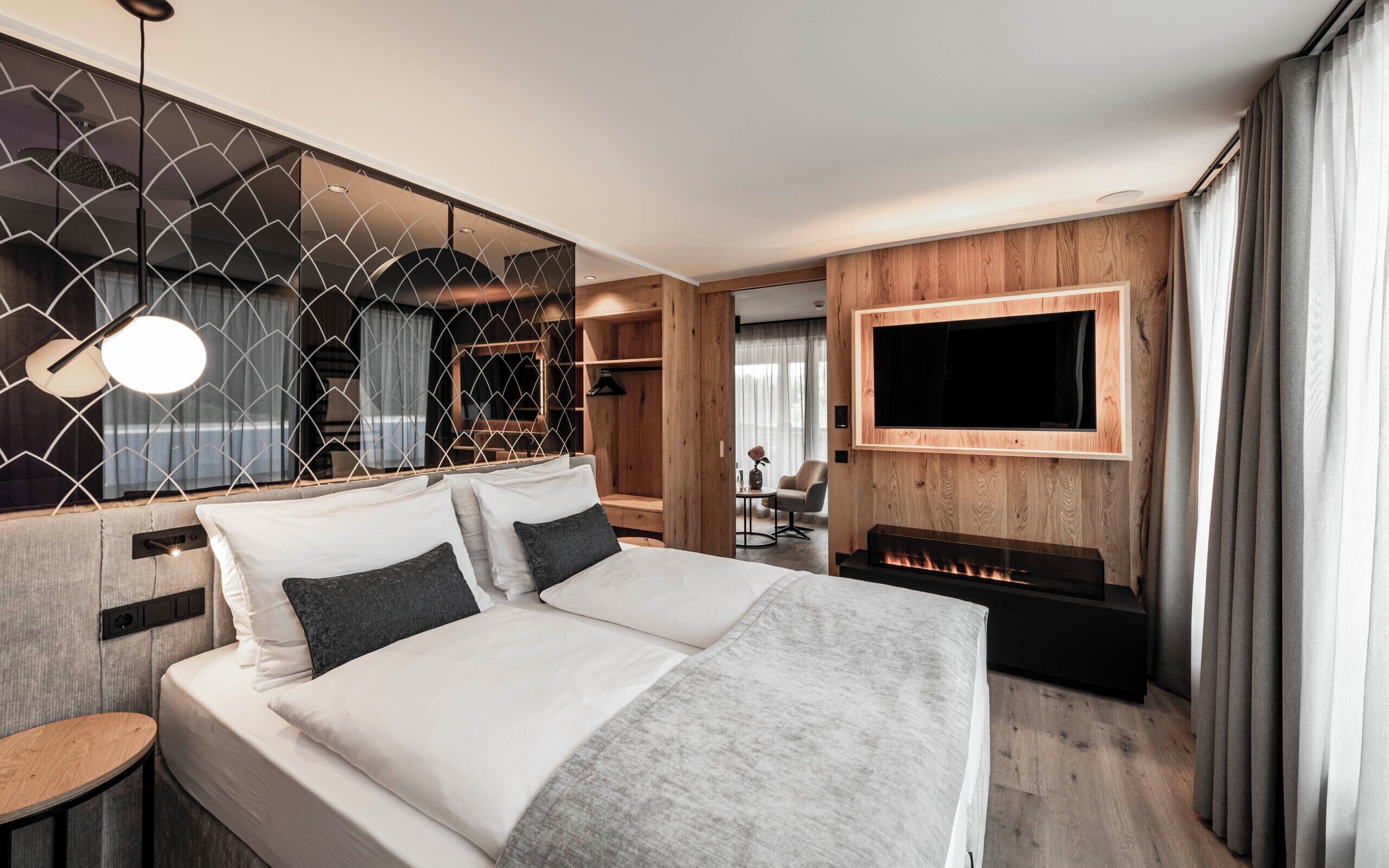 Een moderne hotelkamer met een groot bed, een aan de muur bevestigde televisie en een haard.