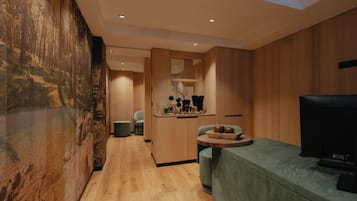 Un interior moderno con pared de madera, un sofá verde, un televisor y una pequeña mesa con objetos decorativos.