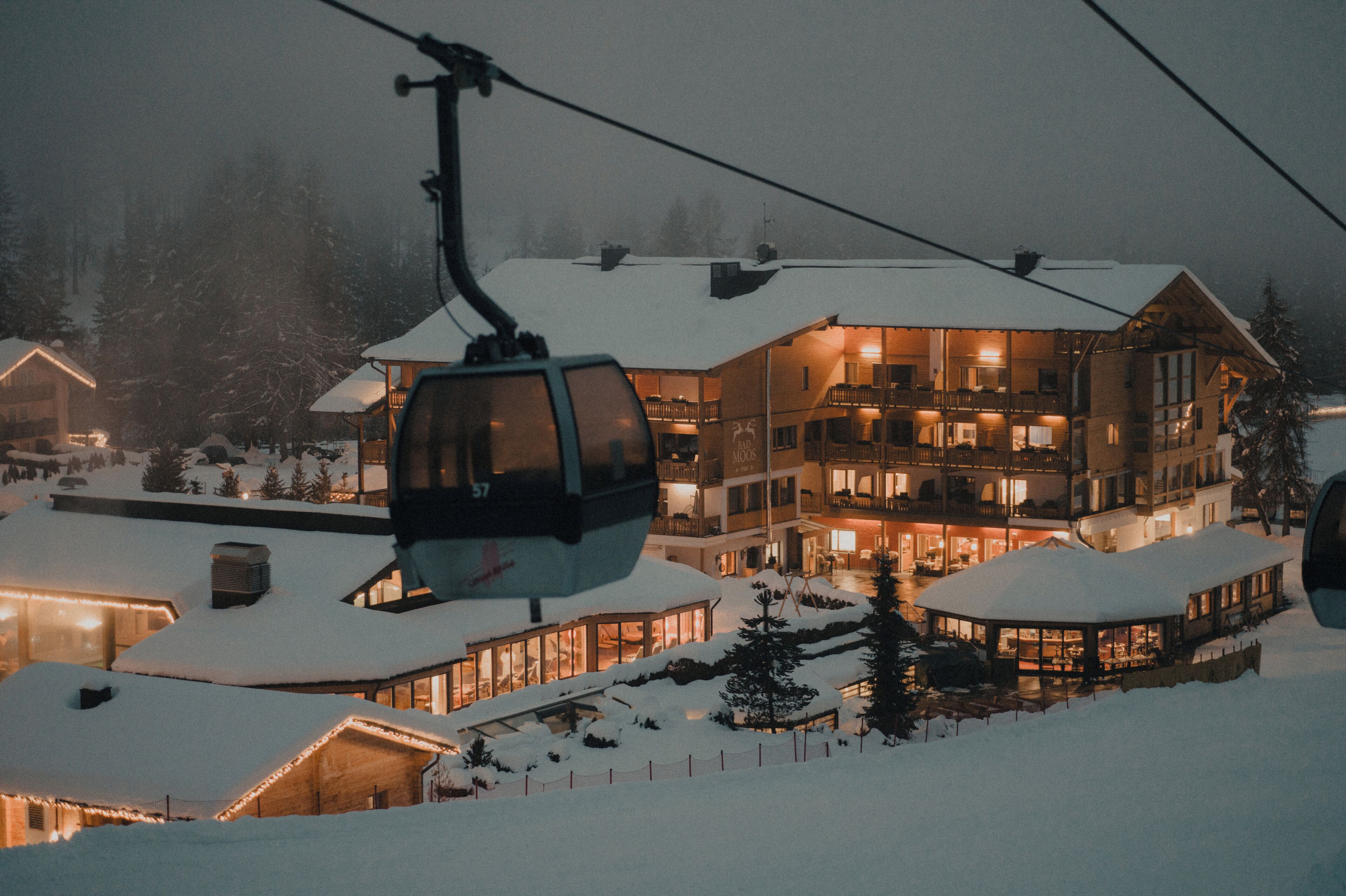 A snow-covered building with multiple balconies, a ski lift, and a well-lit interior.
