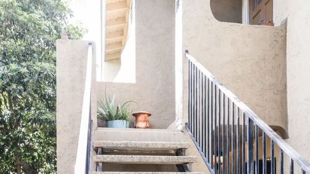 A concrete staircase with metal railings, a potted plant, and a small window. - Escondido Urban Stay - Stylish 2BR Apartment (Escondido)