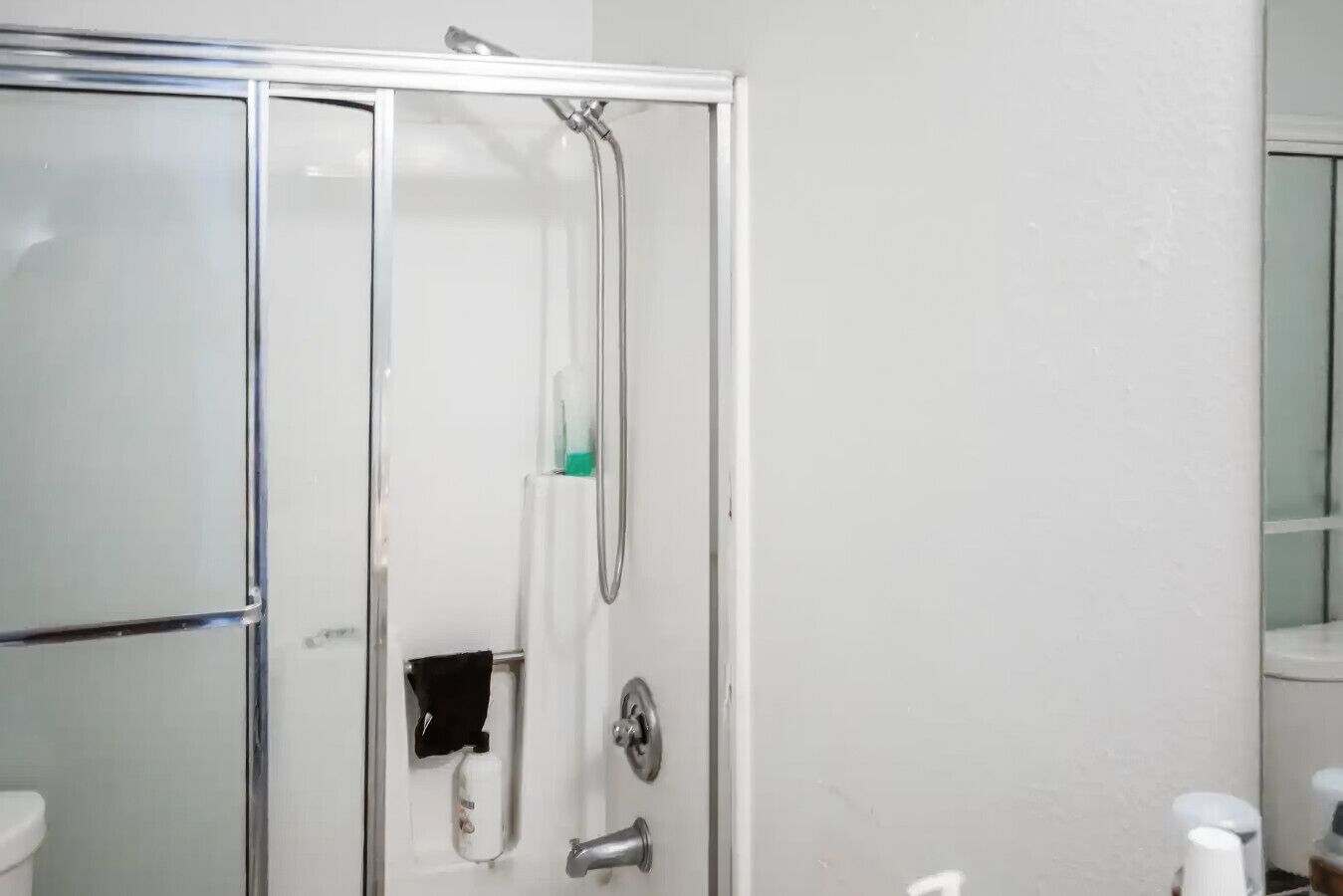 A bathroom with a glass-enclosed shower, a toilet, and a sink.