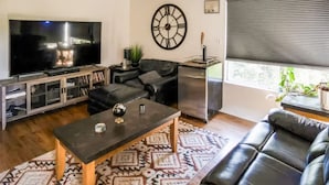 A living room with a TV, sofa, coffee table, and a clock on the wall. - Escondido Urban Stay - Stylish 2BR Apartment (Escondido)