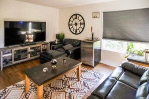 Ein Wohnzimmer mit Fernseher, Sofa, Couchtisch und einer Wanduhr.