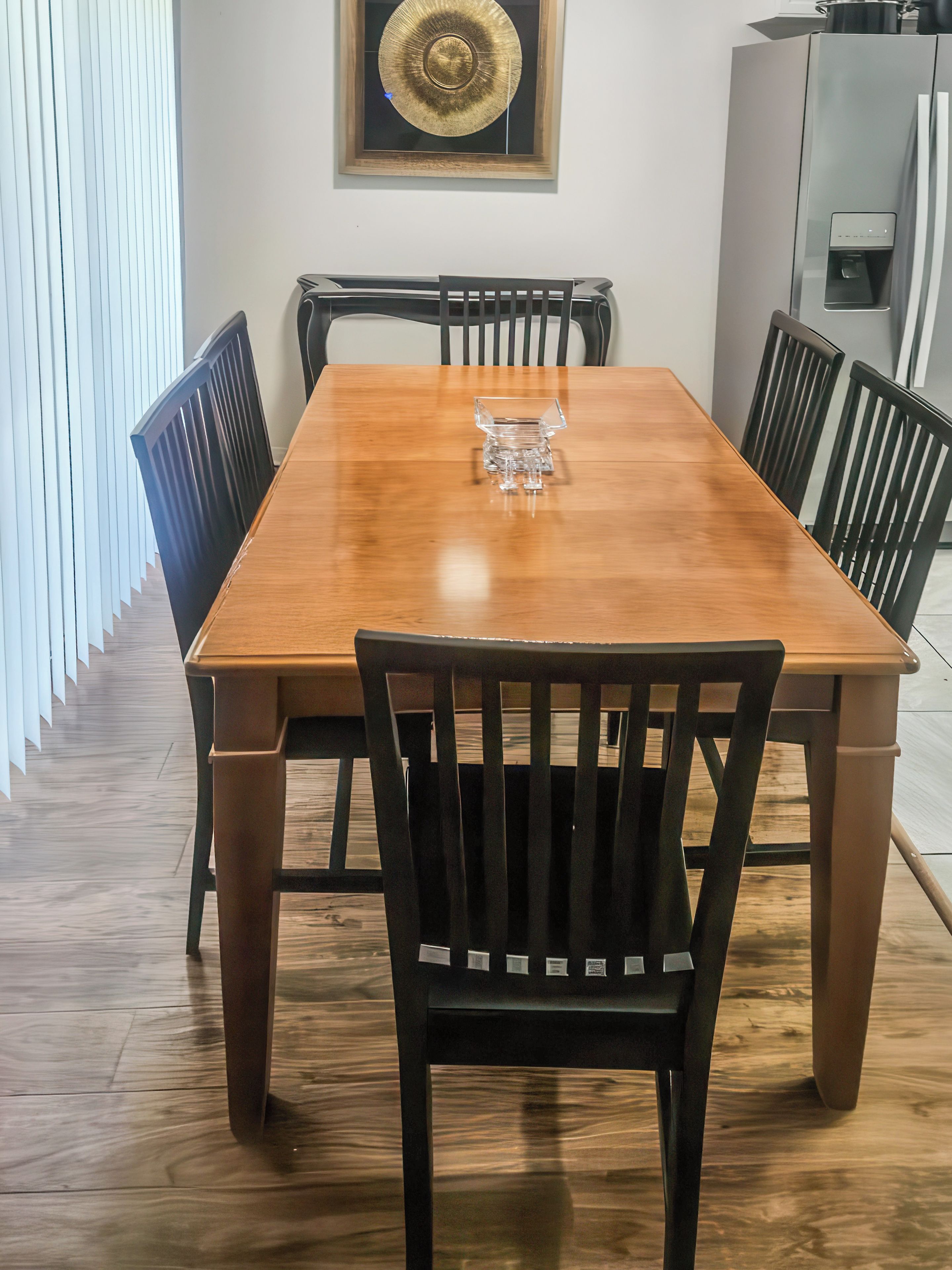 A dining area with a wooden table, black chairs, and a clear glass centerpiece.