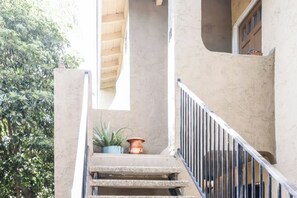 Un escalier avec une rampe en métal, un pot de fleurs et une porte en haut.