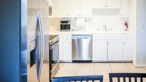 A modern kitchen with white cabinets, a stainless steel refrigerator, a dishwasher, and a coffee maker. - Escondido Urban Stay - 2BR Apartment (Escondido)