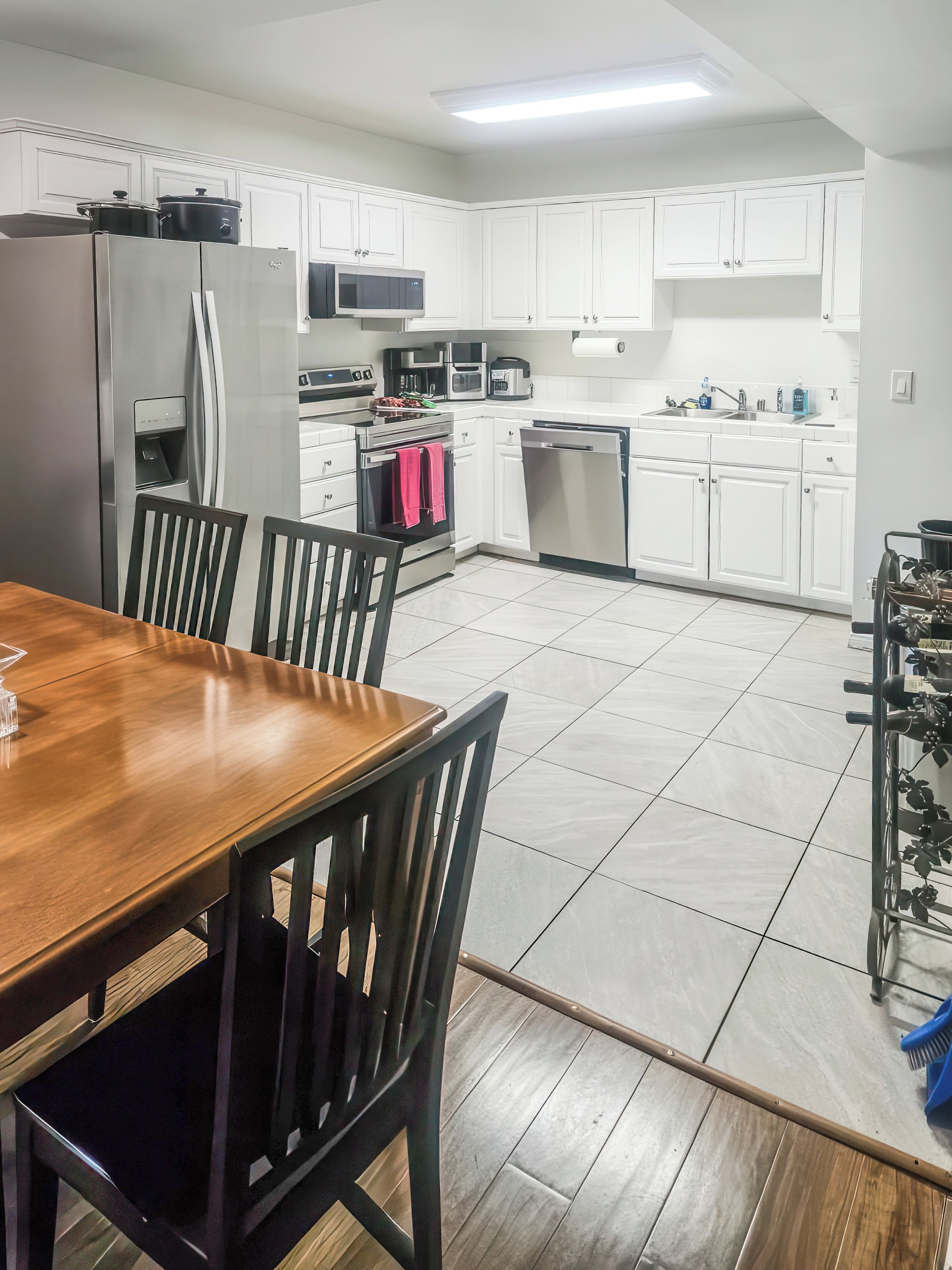 Una cocina moderna con armarios blancos, electrodomésticos de acero inoxidable y una mesa de comedor de madera con sillas.