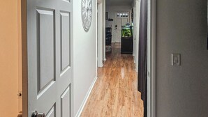 A hallway with a wooden floor, a door with a keyhole, and a wall clock. - Escondido Urban Stay - 2BR Apartment (Escondido)