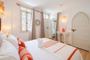 A hotel room with a bed, a bedside table, a mirror, a window with curtains, and a door. - Riad Sultanes-Peaceful haven with private Jacuzzi (Marrakech)
