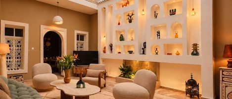 Amplia sala de estar con techo alto, chimenea y una colección de estantes con adornos.