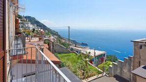 Uma cidade costeira com casas em terraços, vista para o mar e céu claro.